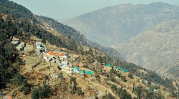 Aerial view of a picturesque village nestled in a tranquil mountain valley with vibrant rooftops.