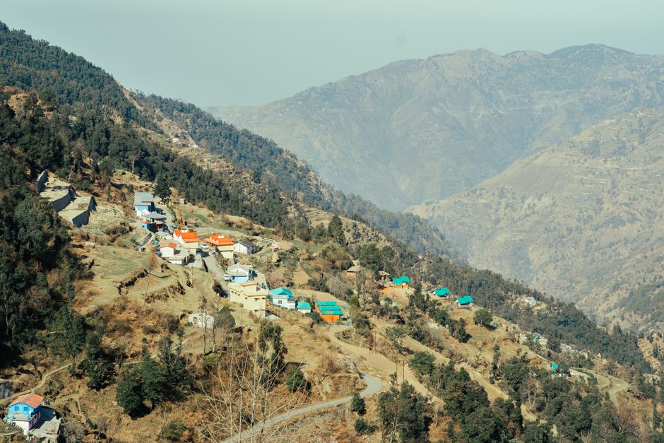 Aerial view of a picturesque village nestled in a tranquil mountain valley with vibrant rooftops.