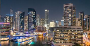 Stunning night view of Dubai Marina with illuminated skyscrapers and reflections on the water.