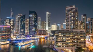 Stunning night view of Dubai Marina with illuminated skyscrapers and reflections on the water.