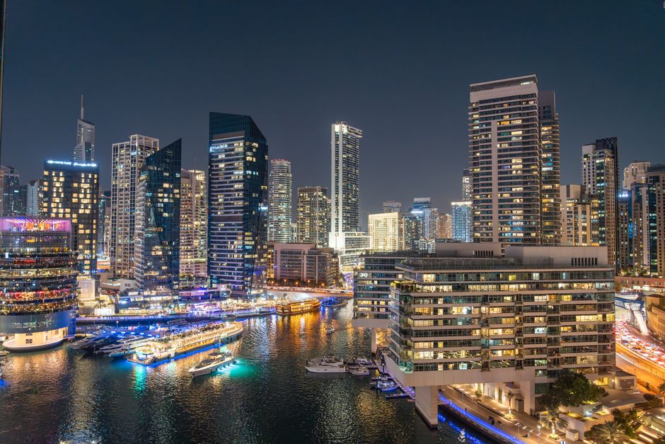 Stunning night view of Dubai Marina with illuminated skyscrapers and reflections on the water.